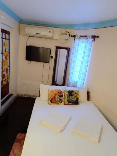 a small room with a bed with a tv on the wall at Kottai Veedu Pondicherry in Pondicherry