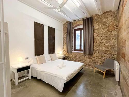 a bedroom with a large white bed and a stone wall at Aptw Pool in heart of old town in Girona
