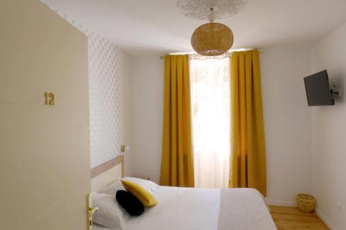 - une chambre avec un lit blanc et des rideaux jaunes dans l'établissement La Tour de Coron, à Belley