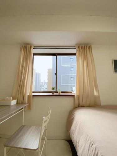 a bedroom with a bed and a window with a chair at 《難波・心斎橋にアクセス最高！》宿泊2名 in Osaka