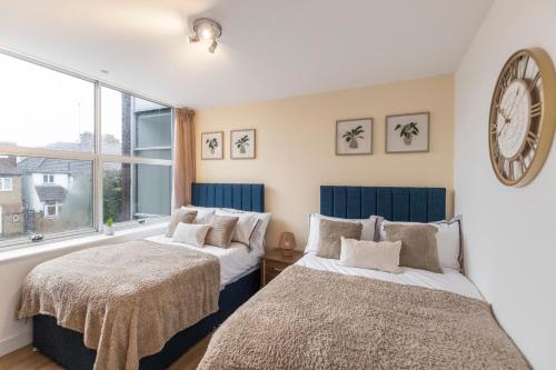 two beds in a room with a clock on the wall at Cosy Retreat in the Heart of Golders Green in London