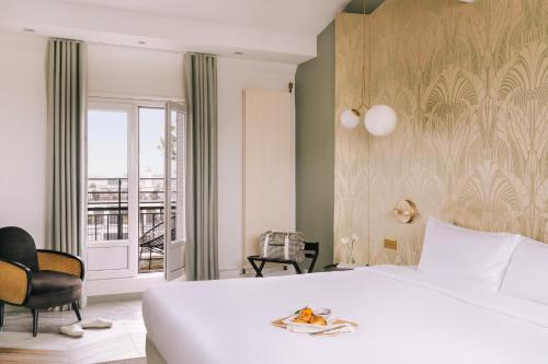 - une chambre avec un grand lit blanc et un balcon dans l'établissement Atala powered by Sonder, à Paris