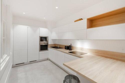 a white kitchen with white cabinets and a sink at L'Elegant Paradoux - 3 sdb - 2 wc - Ascenseur - Parking - Plein Centre in Toulouse