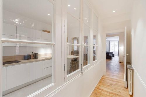 a white kitchen with white cabinets and a hallway at L'Elegant Paradoux - 3 sdb - 2 wc - Ascenseur - Parking - Plein Centre in Toulouse