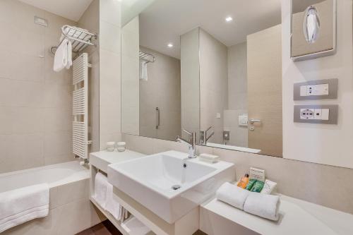 a white bathroom with a sink and a bath tub at Hilton Garden Inn Venice Mestre in Mestre