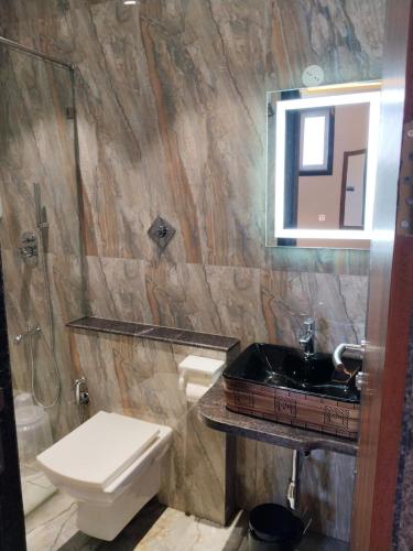 a bathroom with a toilet and a sink and a mirror at Hotel AK International - Chennai in Chennai