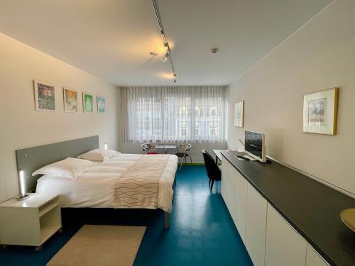 a bedroom with a bed and a desk with a television at Domus Hotel in Luxembourg