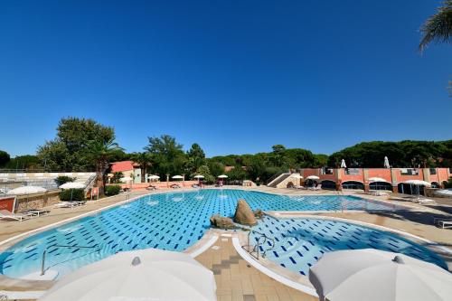 una gran piscina con sombrillas en un complejo en Colostrai Hotel Club, en San Priamo