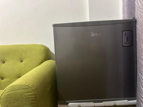 a television sitting next to a green couch at Roxy Apartment Kuching in Kuching