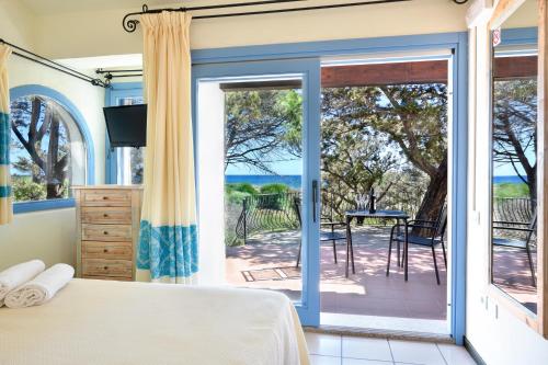 1 dormitorio con 1 cama y puerta corredera de cristal en Colostrai Hotel Club, en San Priamo