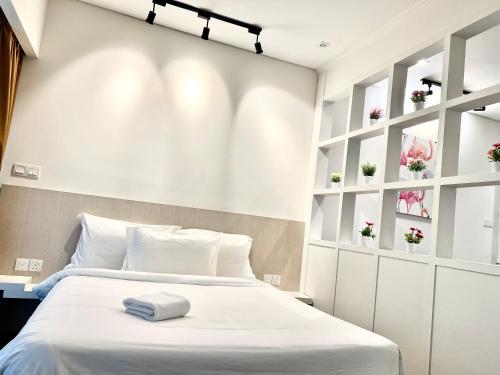 a bedroom with a white bed and white shelves at Summer suites KLCC by cozy stay in Kuala Lumpur