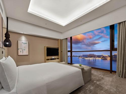 a bedroom with a large white bed and a large window at Hilton Shanghai Songjiang Guangfulin in Songjiang