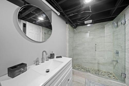 a bathroom with a sink and a mirror and a shower at Elegant Oasis 4 Bedroom Home Away from Home in Utica