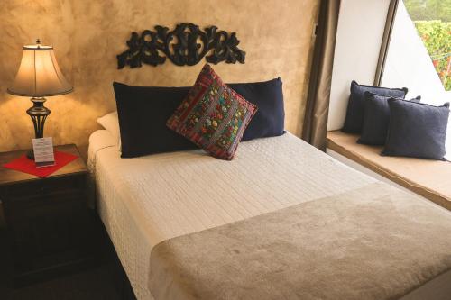 a bedroom with a bed with a lamp and pillows at Hotel Posada de la Luna in Antigua Guatemala