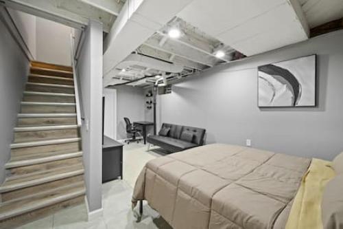 a bedroom with a bed and a staircase with a stair case at Urban Elegance Retreat in Downtown Rochester in Rochester