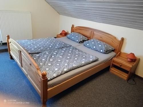 a wooden bed with blue and white sheets and pillows at Ferienhof Welsch Wohnung 2 in Großefehn 