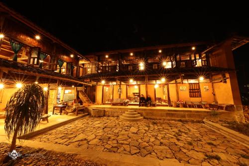 a building with a courtyard at night with lights at Dinh Đá H'Mông - Karsterly Rock Lodge in Dồng Văn
