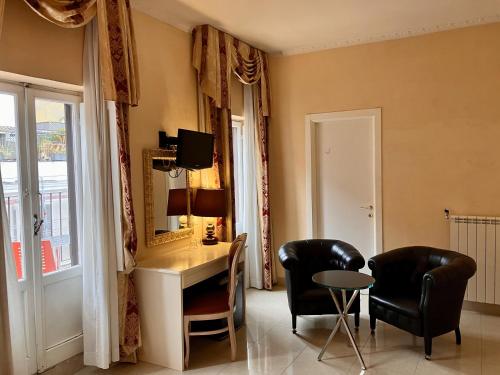 ローマにあるホテル アーダレリの椅子2脚、デスク、鏡が備わる客室です。