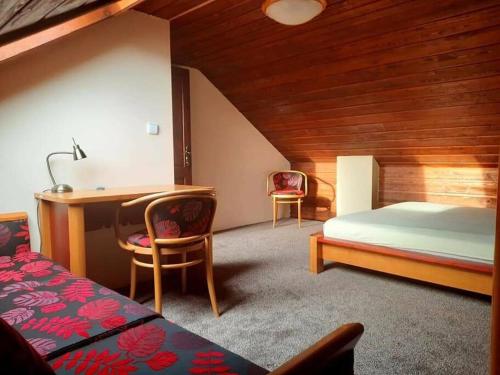ein Schlafzimmer mit einem Bett und einem Schreibtisch sowie einem Bett und einem Stuhl in der Unterkunft Domček v Tatrách in Poprad