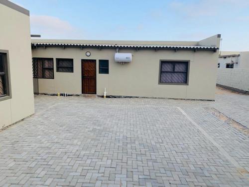 a white building with a brick driveway in front of it at TALITHA'S SELF-CATERING ACCOMONDATION in Walvis Bay