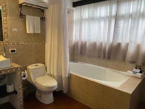 a bathroom with a toilet and a tub and a sink at Hotel Posada de la Luna in Antigua Guatemala