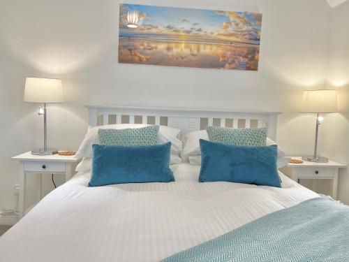 a bedroom with a white bed with blue pillows at Lundy Lookout 5 minutes drive to beach Hot tub in Westward Ho