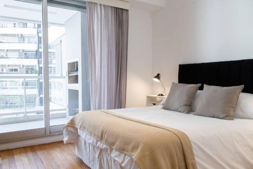 um quarto com uma cama grande e uma janela grande em Abedul Deluxe Apartment em Buenos Aires
