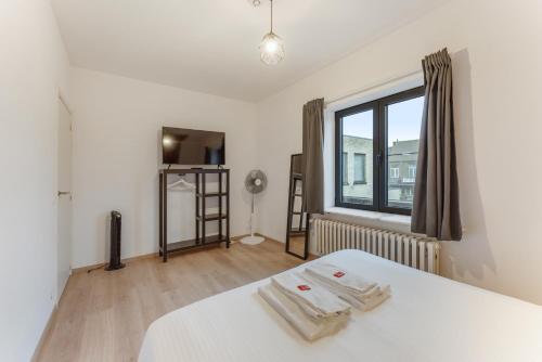 a bedroom with a white bed and a window at General Sixty-Seven by Romy&Travis in Bruges