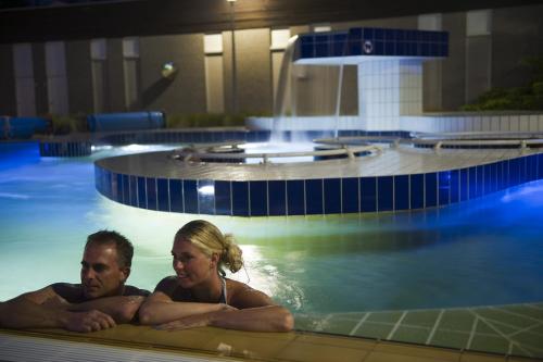 een man en vrouw die in een zwembad liggen bij Vakantiepark Klein Vink - Boulevard 27 in Arcen