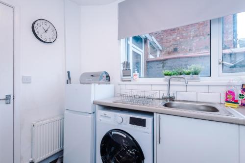 a kitchen with a washing machine and a sink at Sleek and Stylish 3 BR Home Mcr in Manchester