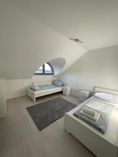 a white bedroom with two beds and a window at Premium Apartment 3 in Dillingen an der Saar