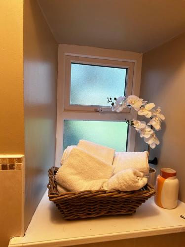 una cesta de toallas sentada en un estante junto a una ventana en Lemonade Cottages and Retreat en Kilrush