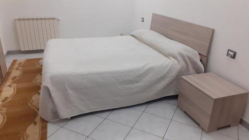 1 cama con manta blanca y mesita de noche en Casa Vacanza Pineta, en Oltrona di San Mamette
