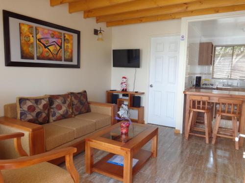 sala de estar con sofá y cocina en Cabanas Piedras Preciosas, en El Quisco