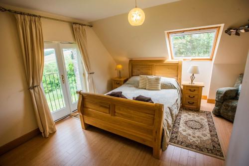 a bedroom with a wooden bed and a window at Errichel House and Cottages in Aberfeldy