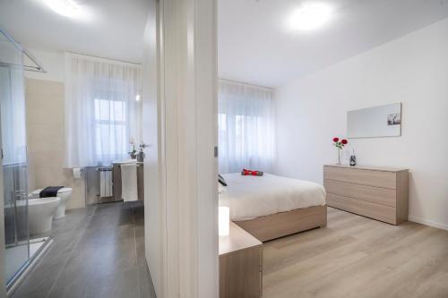 a white bedroom with a bed and a bathroom at Marino's Apartment in Udine