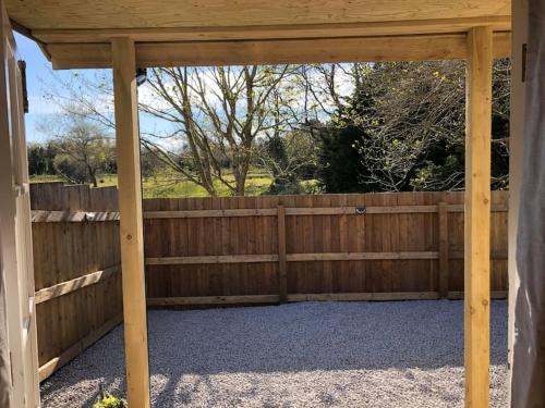 a wooden privacy fence with a wooden pergola at Fairway Lodge in Saint Erth