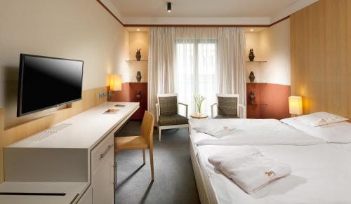 a hotel room with two beds and a desk at Alexandria Spa & Wellness Hotel in Luhačovice