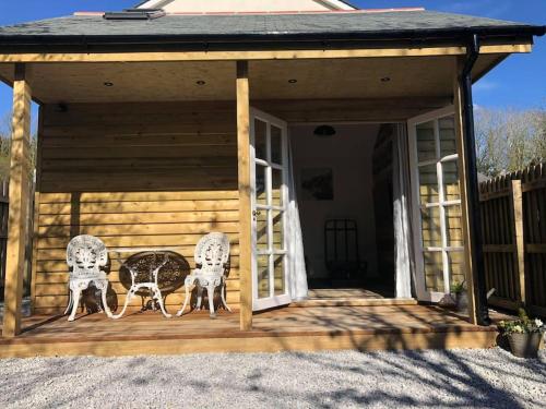 dwa krzesła siedzące na ganku domu w obiekcie Fairway Lodge w mieście Saint Erth