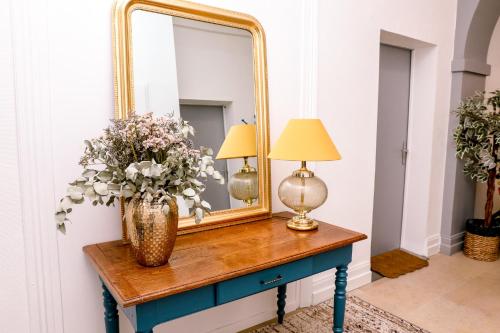 a mirror and a vase with flowers on a table at Le Jules Appart'Hotel in Romans-sur-Isère