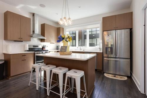 a kitchen with a island with bar stools and a refrigerator at Modern Townhome, Large Game Room with Ping Pong, 10min to Downtown! Sleeps 10! in Nashville