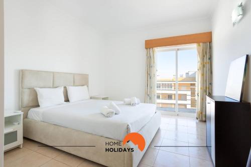 a bedroom with a bed with a tv and a window at #199 Flamingo 1108 by Home Holidays in Portimão