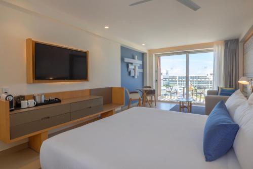 a hotel room with a large bed and a television at Royalton Splash Riviera Cancun, An Autograph Collection All-Inclusive Resort in Cancún