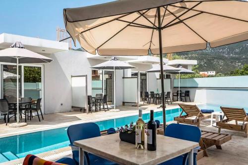 a patio with a table and umbrellas next to a pool at BLUE STAR APARTHOTEL in Nydri