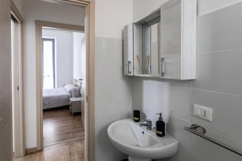 a white bathroom with a sink and a mirror at A due passi dal centro, Valentino's Apartment in Casale Monferrato