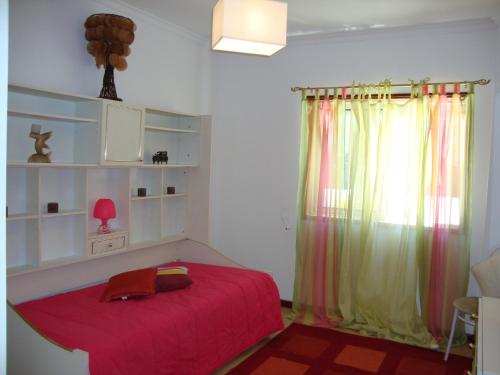 a bedroom with a red bed and a window at Apartamento Aracelli in Ermesinde