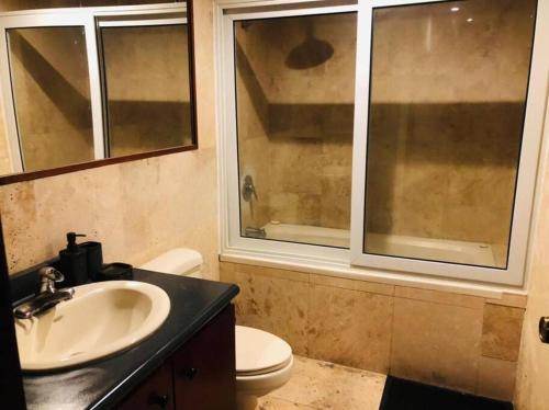 a bathroom with a sink and a toilet and a window at apartamento avenida las américas in Guatemala