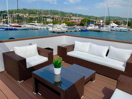 una terraza con 2 sillas, una mesa y barcos en FLOATING SEA HOUSE AURORA, en Portorož