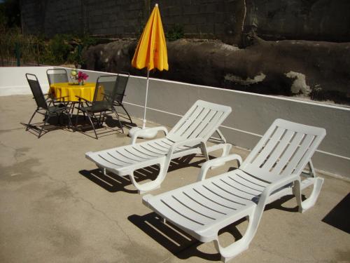 three chairs and a table with an umbrella at Apartamento Aracelli in Ermesinde