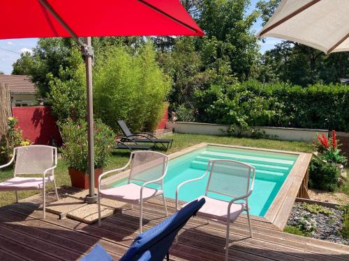 - une piscine avec des chaises et un parasol rouge dans l'établissement villa 7 chambres piscine 35 mn Paris, à Verneuil-sur-Seine